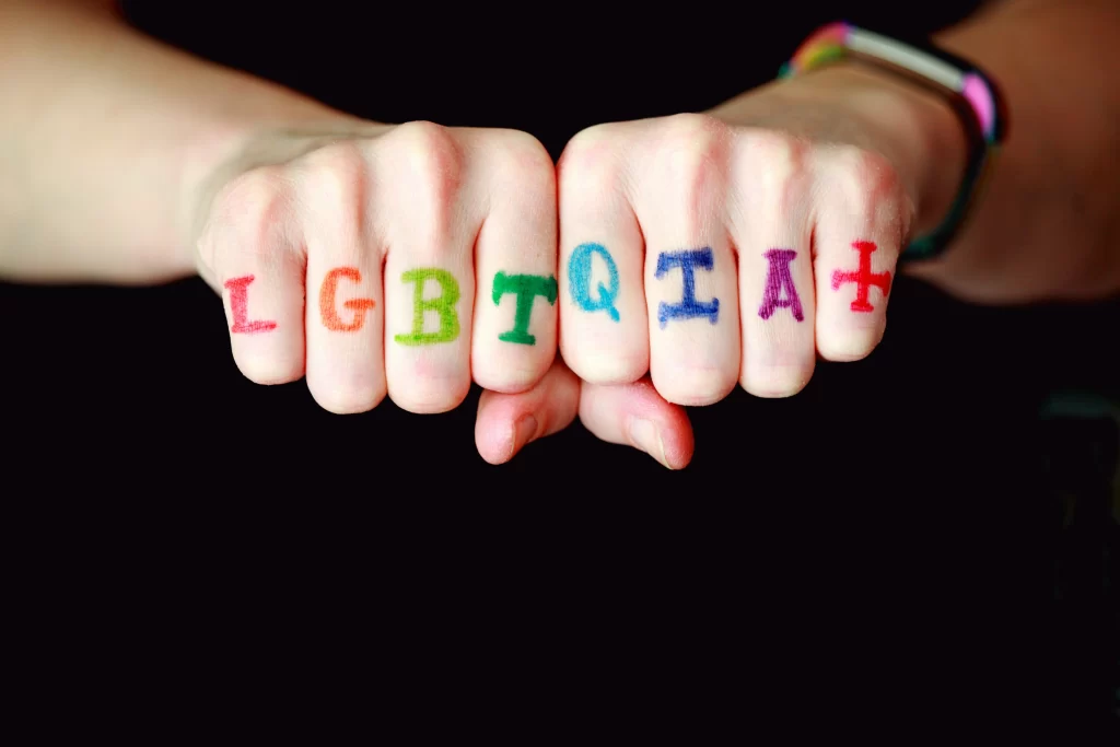 a person holding his fists together with LGBTQIA Plus written on his knuckles