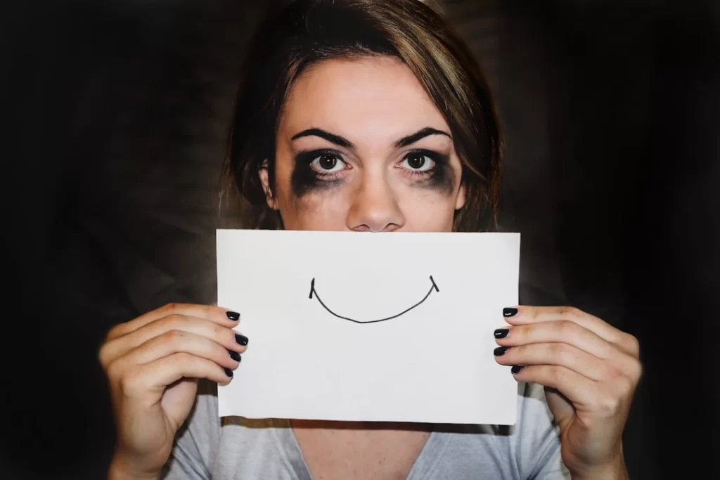 sad person covering her mouth with a white printer paper with a smile on it