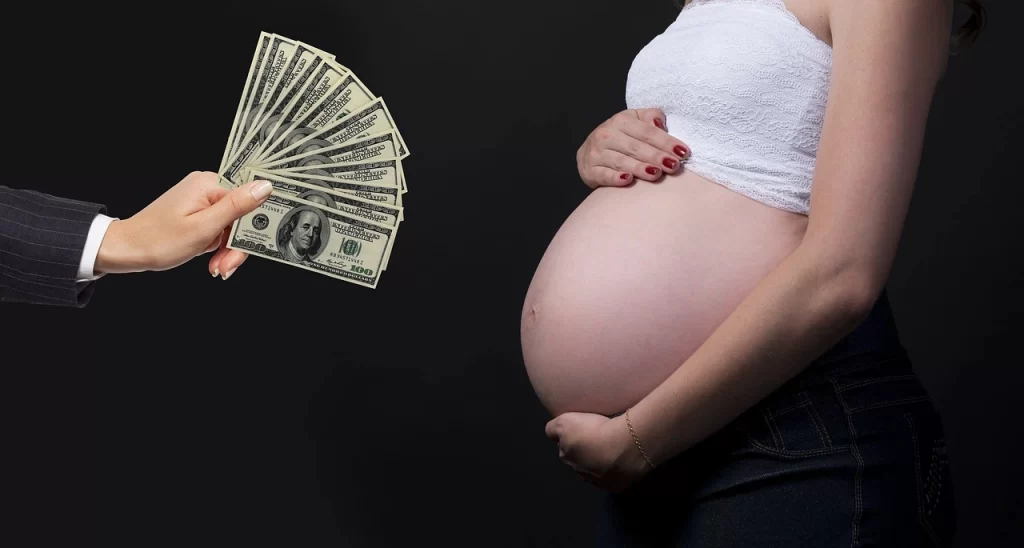 Intended parent holding money in front of a pregnant woman's belly